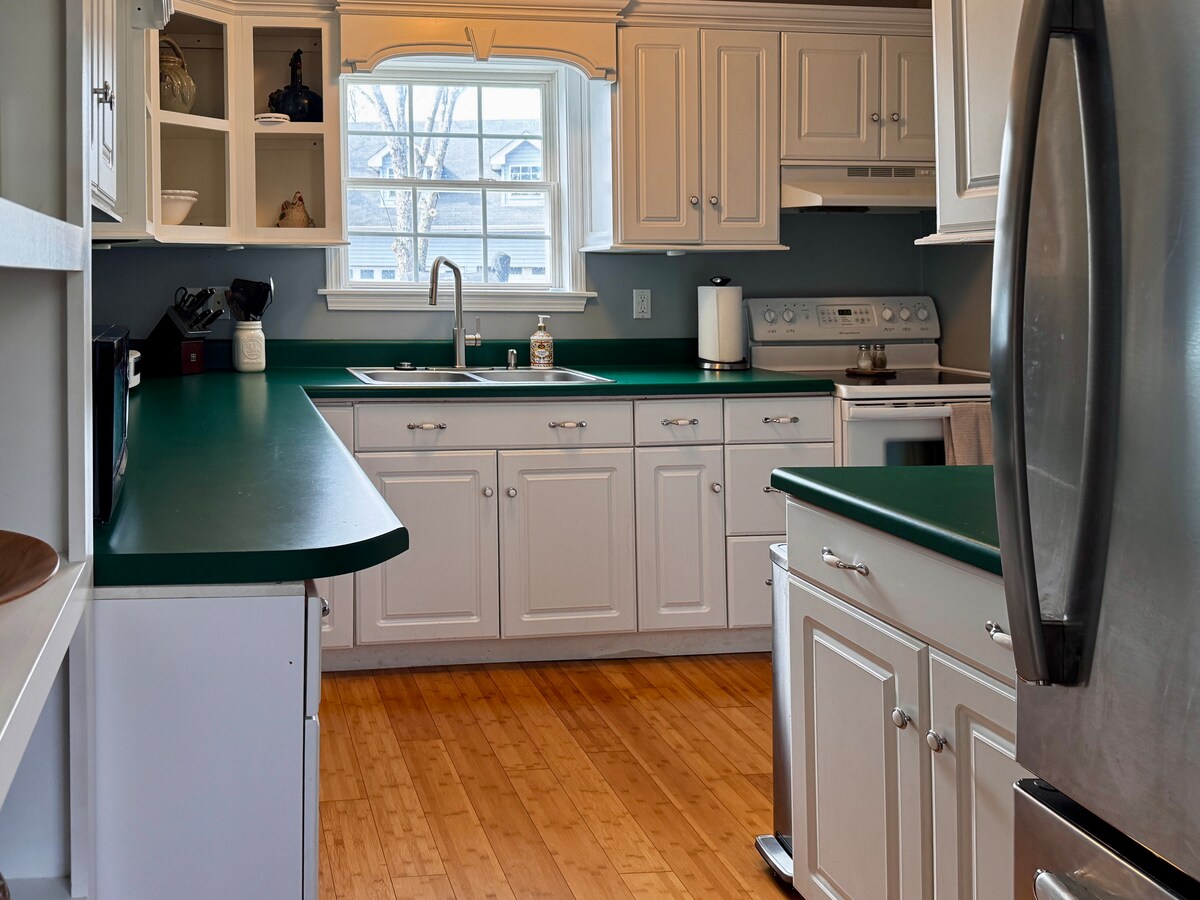 Full kitchen with green counters and white cabinetry